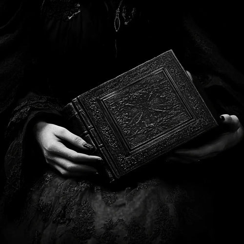 An image of a woman holding a grimoire depicting the history of witchcraft